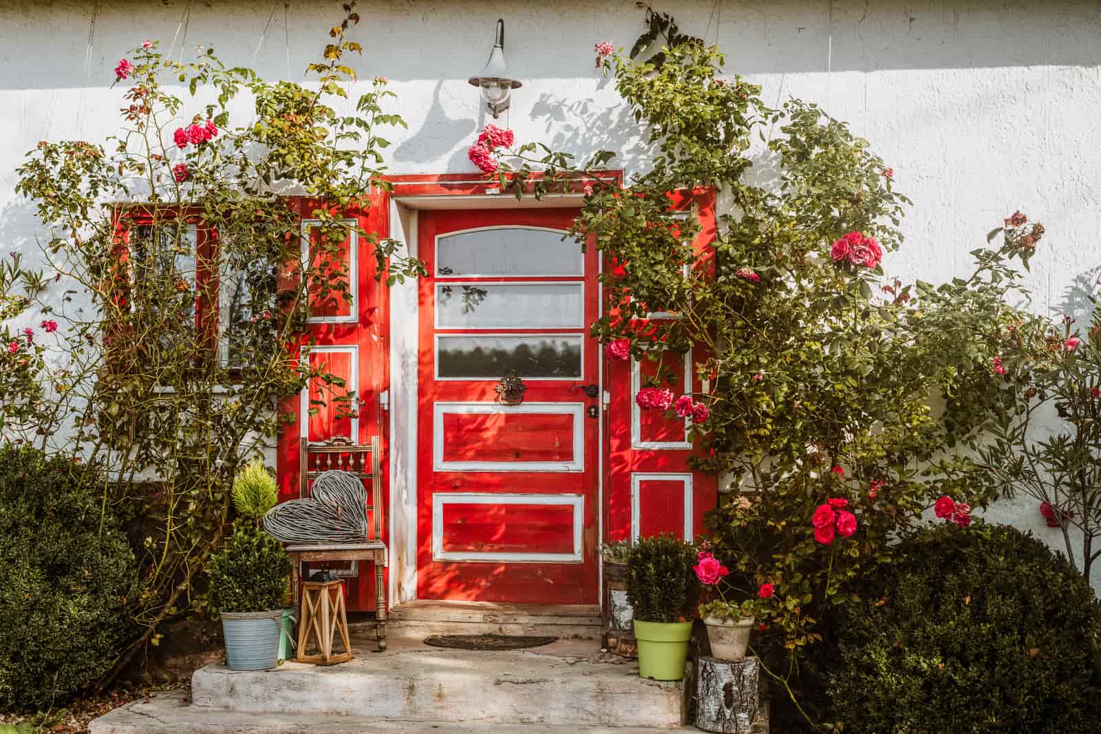 A painted red front door framed by spring greenery